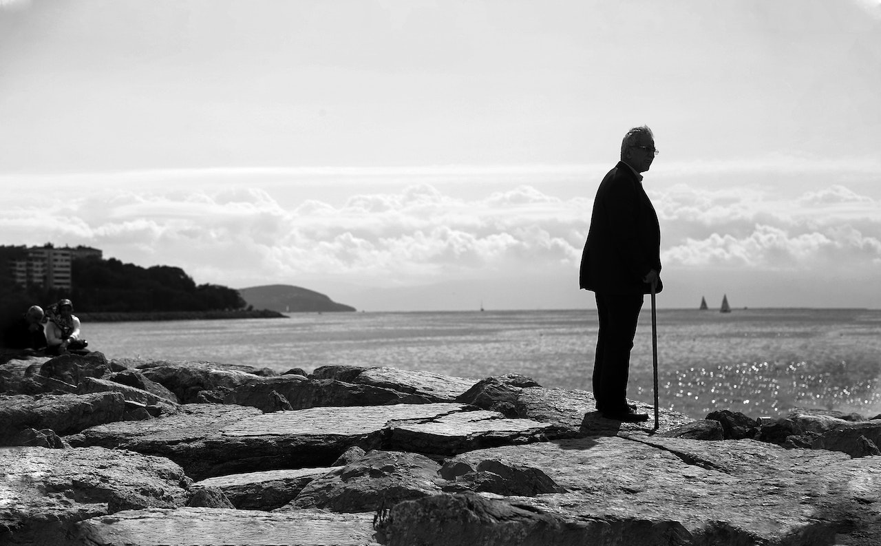 Man with a Walking Stick Standing on Rock | Veteran Car Donations
