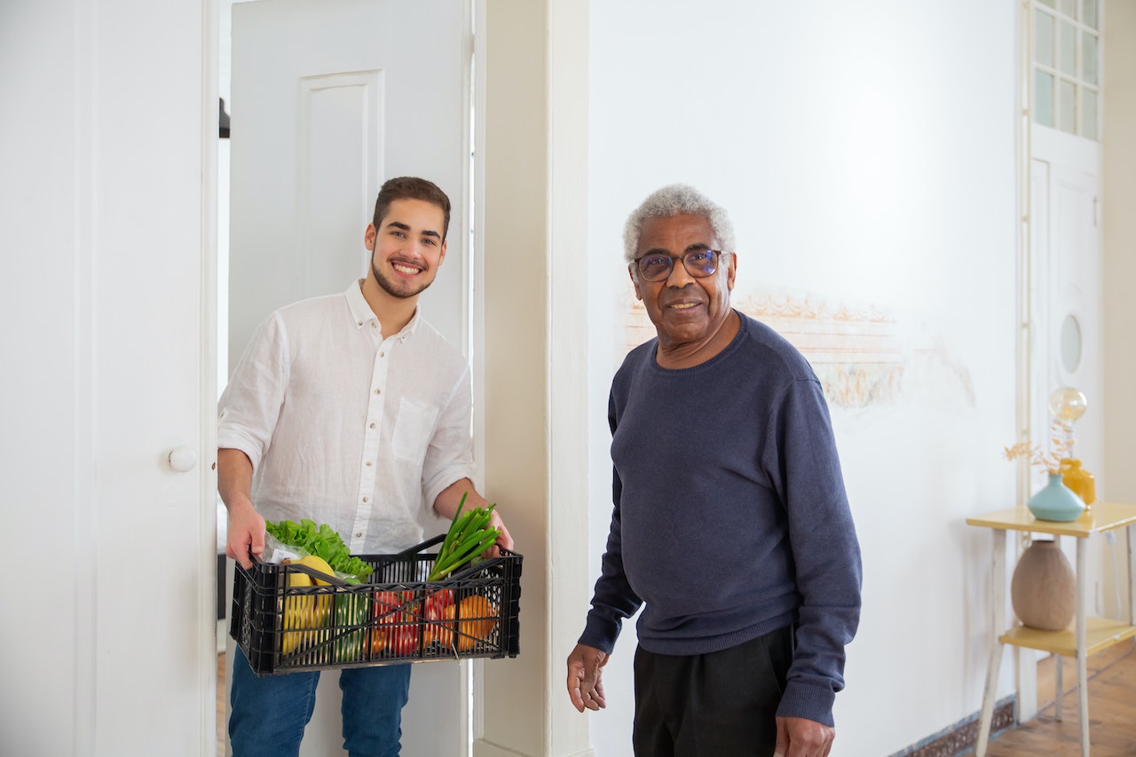 A Man Holding a Plastic Crate with Fruits and Vegetables | Veteran Car Donations
