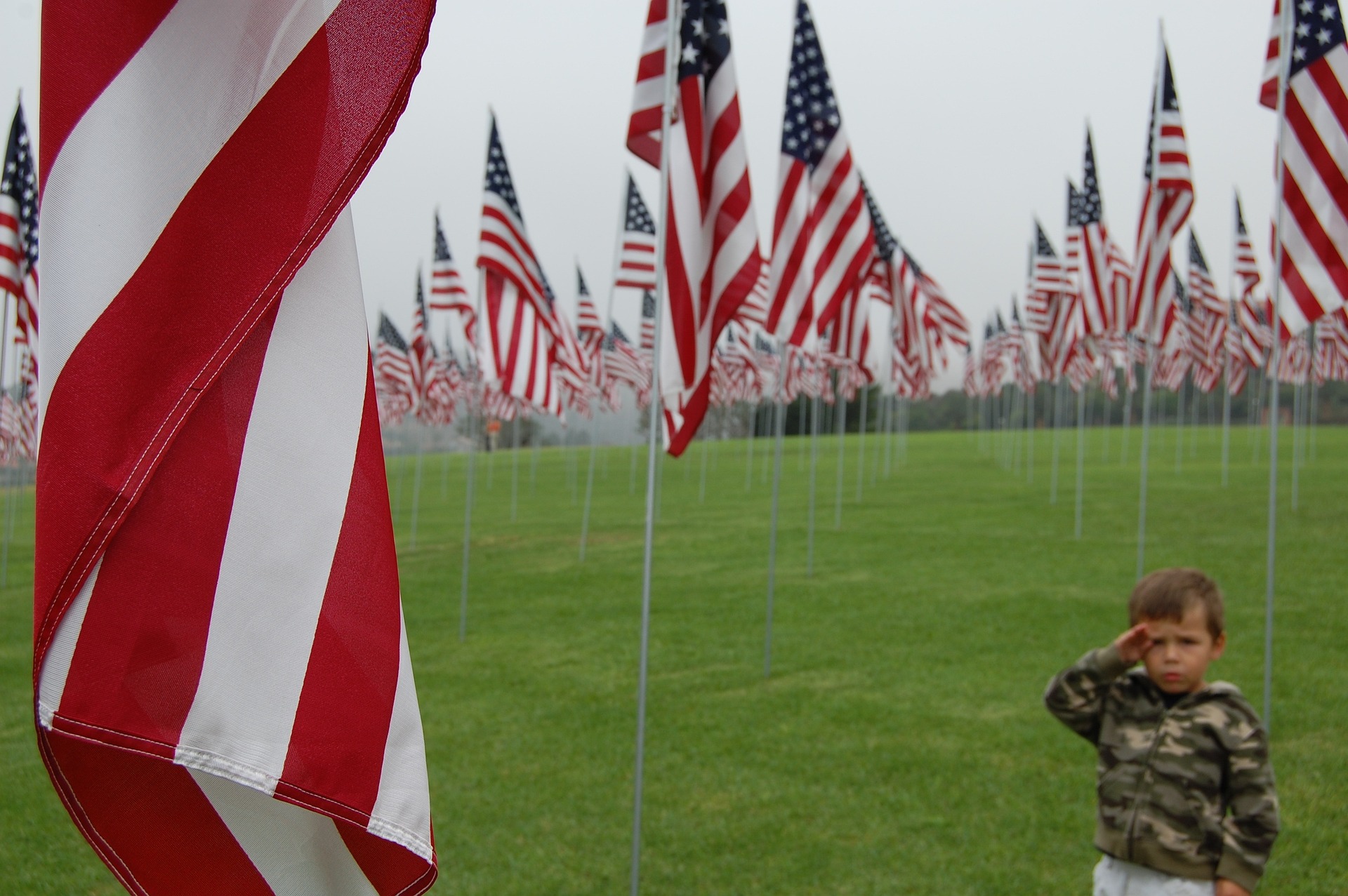 Child saluting to US flags | Veteran Car Donations