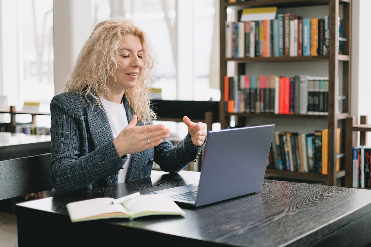 Smiling woman having video chat via laptop in library | Veteran Car Donations
