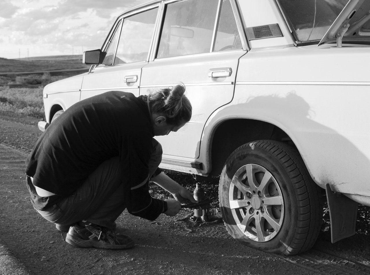 A Man Fixing a Flat Tire | Veteran Car Donations
