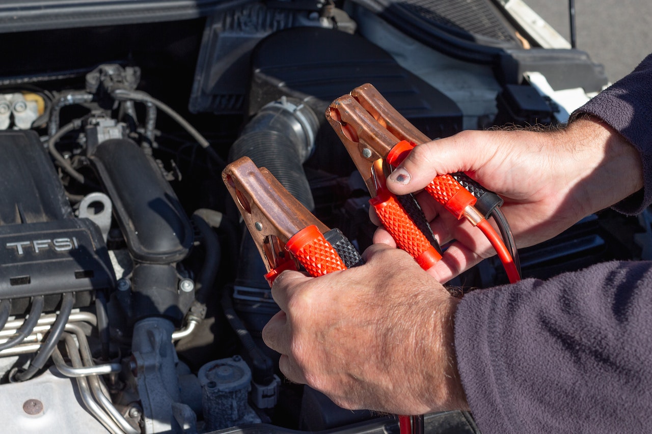 Man Holding Clips in Front of a Car Engine | Veteran Car Donations