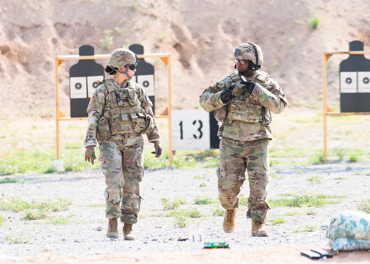 Man and a Woman in Camouflage Uniform Standing on Ground | Veteran Car Donations
