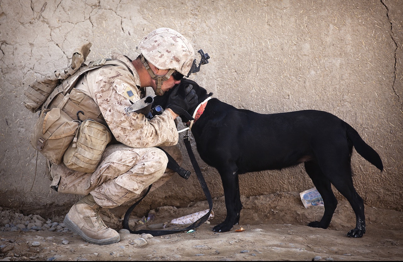 Soldier and Black Dog Cuddling | Veteran Car Donations
