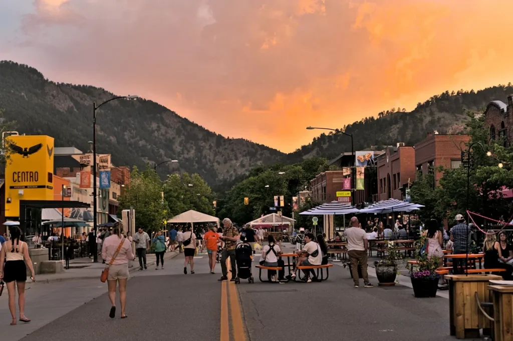 A group of people walking on a street in Boulder with mountains in the background