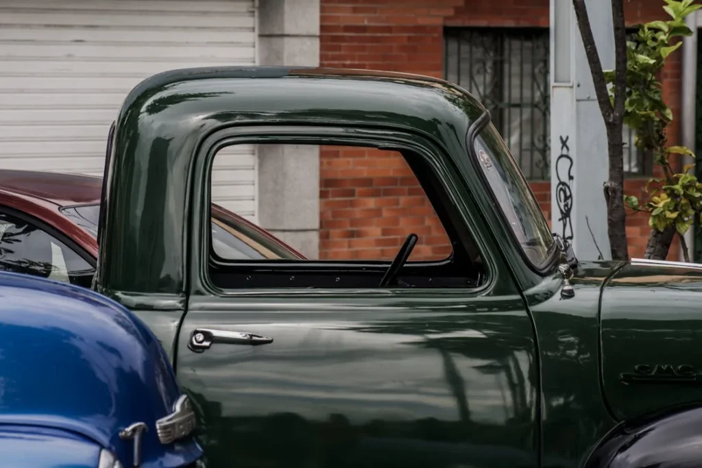 Green vintage car parked beside brown brick building