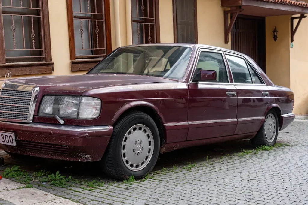 Vintage Maroon Sedan Parked on Cobblestone Street