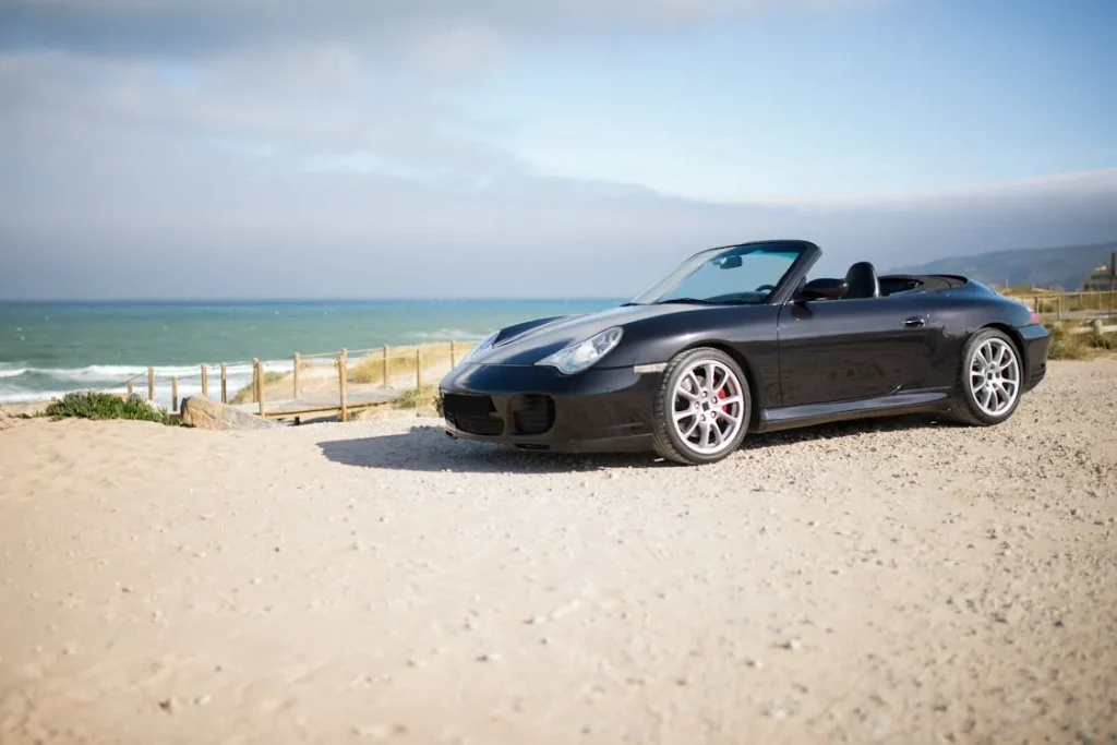 A cabriolet parked near a beach