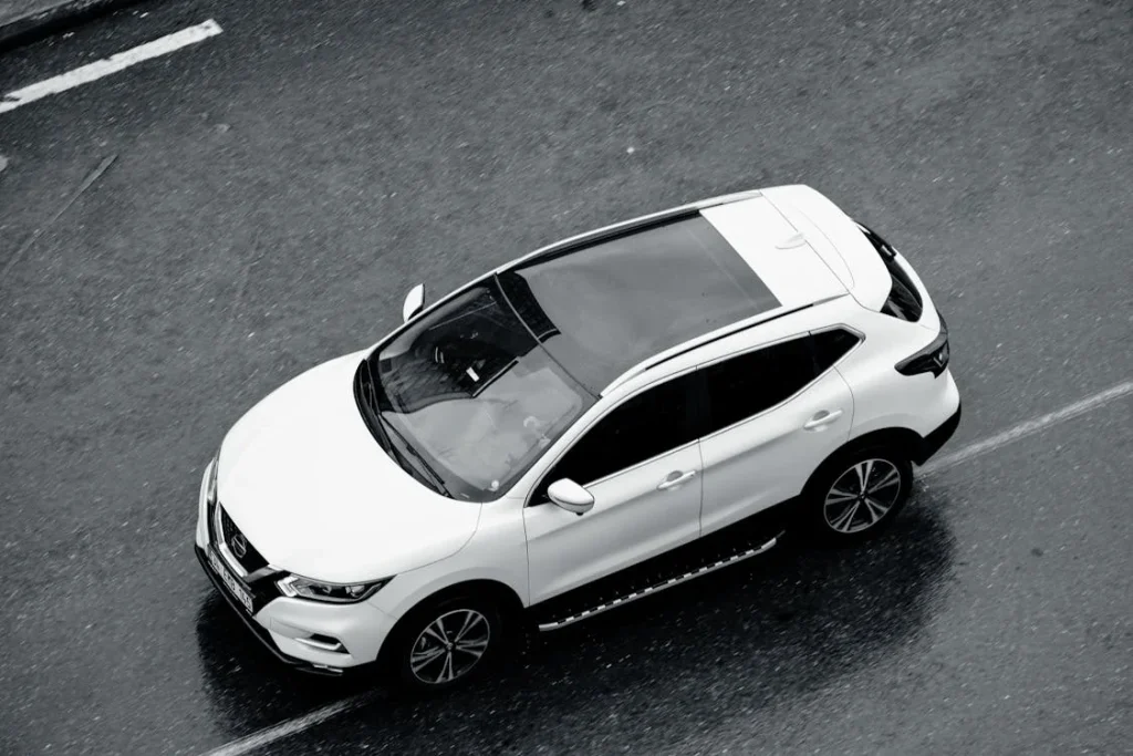 White SUV driving along a wet city road