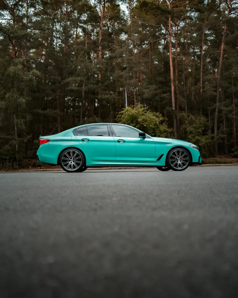 Green sedan parked on a forest road