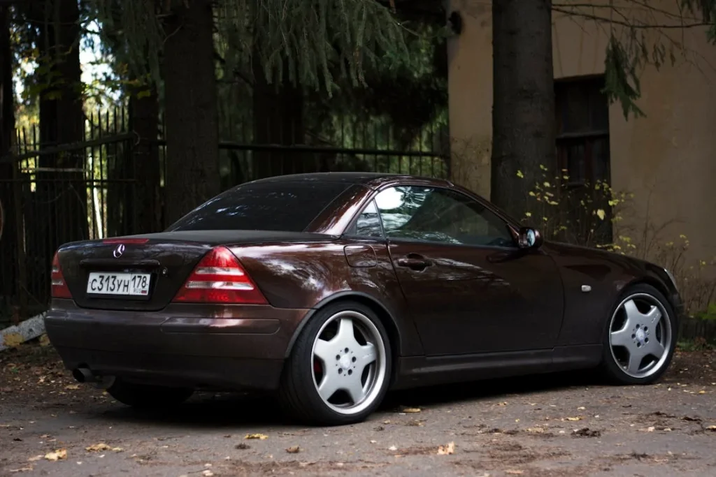 Photo of a brown car parked on pavement under an iron fence