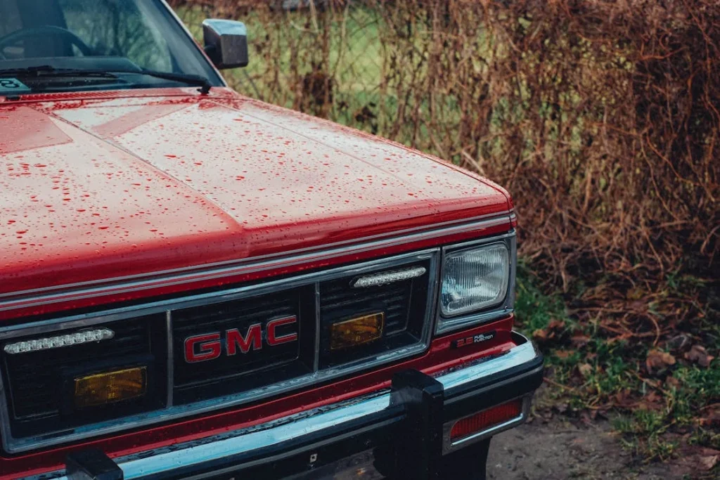 Red classic GMC Jimmy car covered with raindrops