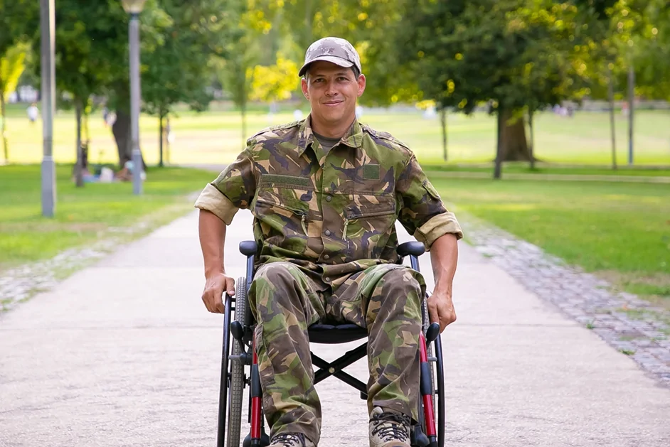 Happy disabled military man in wheelchair wearing camouflage uniform