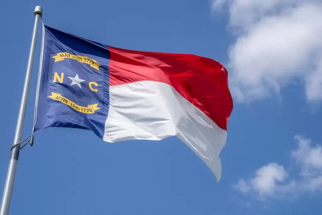 North Carolina state flag on a pole under a blue sky