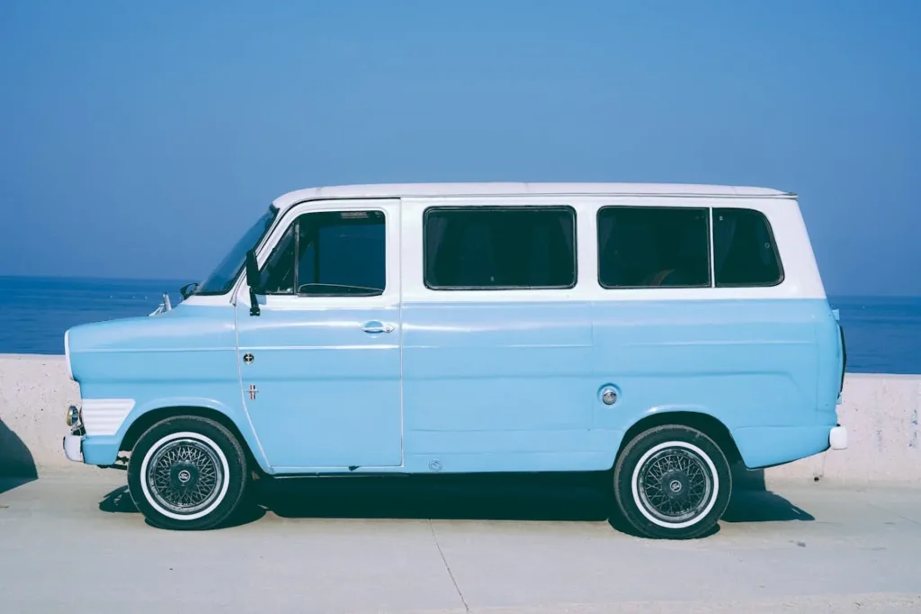 Blue and white minivan parked outdoors with a coastal backdrop