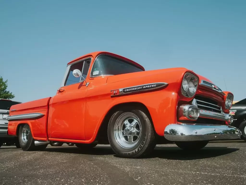 Red vintage car on gray asphalt road during daytime