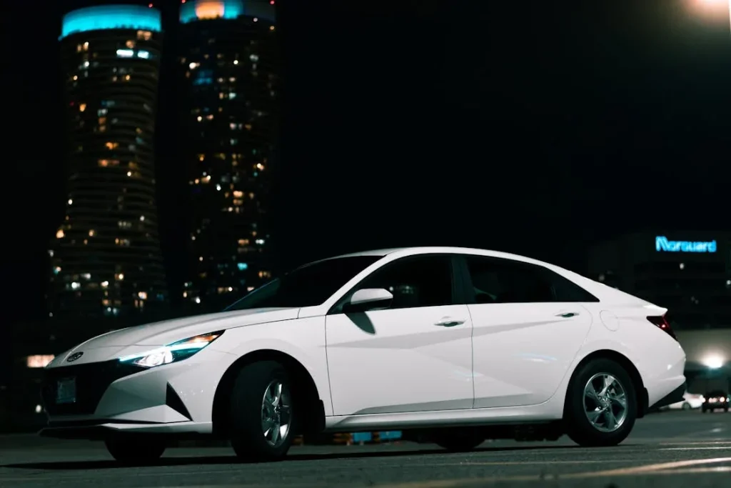 White sedan parked on a pavement at night