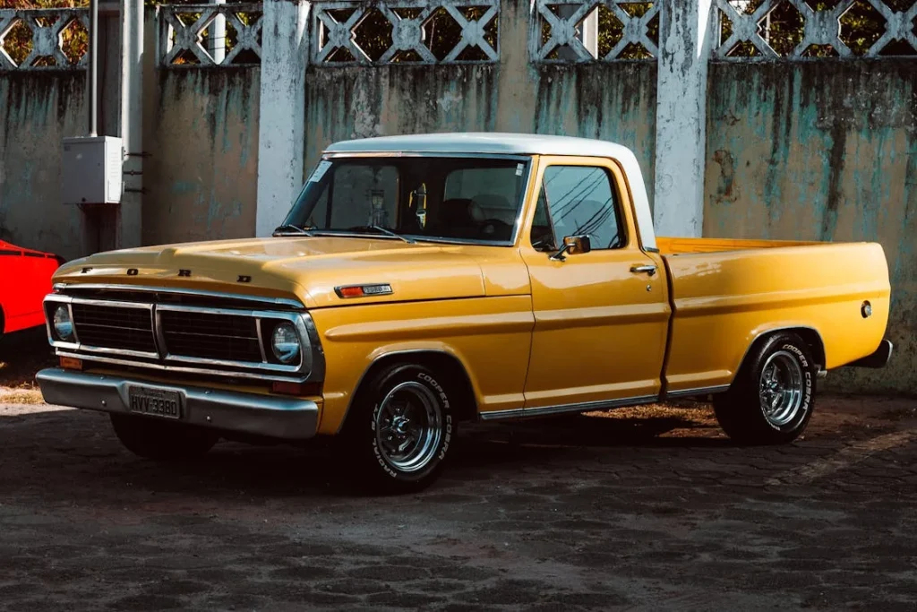 Yellow Ford vintage car parked near a concrete wall