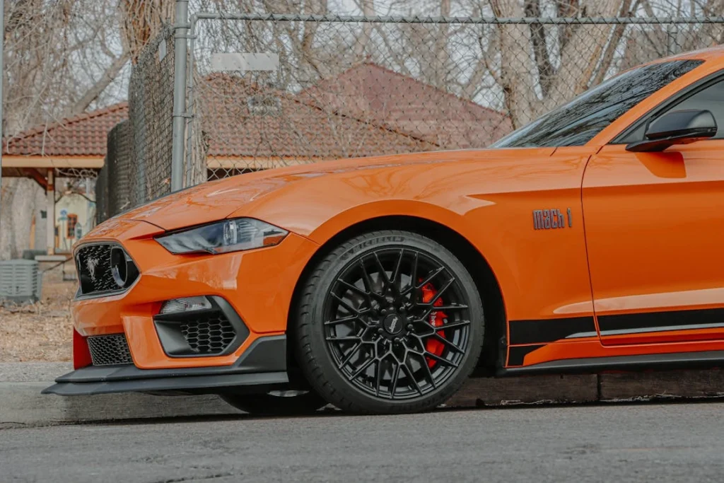Orange car parked near a metal fence