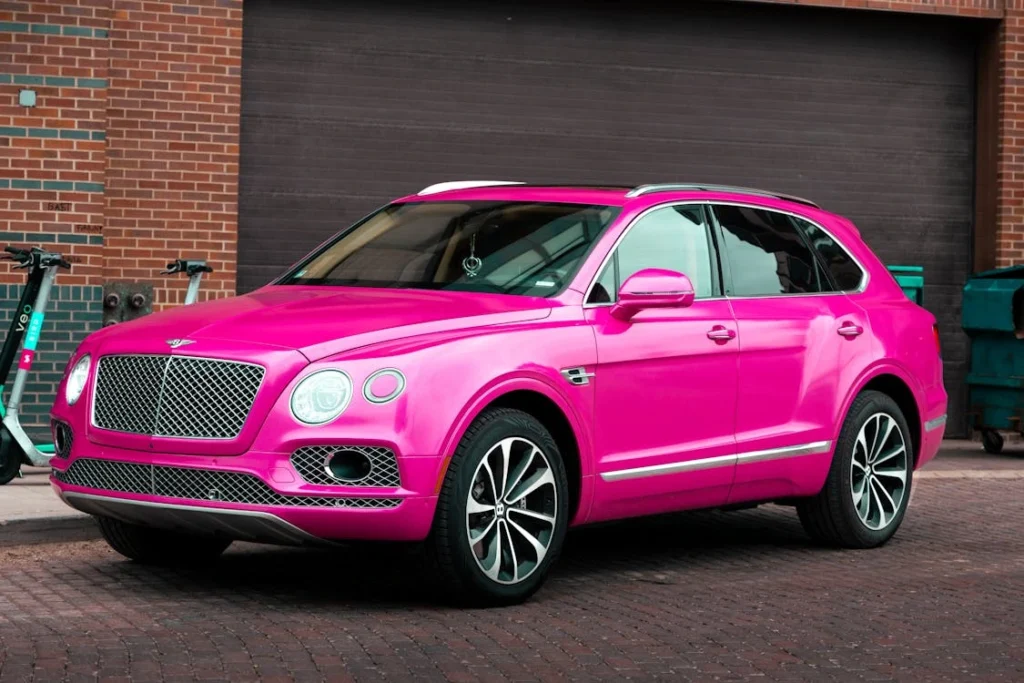 Vibrant pink luxury SUV parked on a brick street in an urban setting