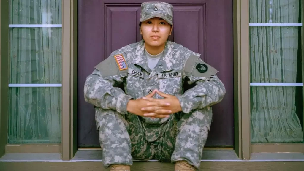 Female army member sitting in front of a closed door